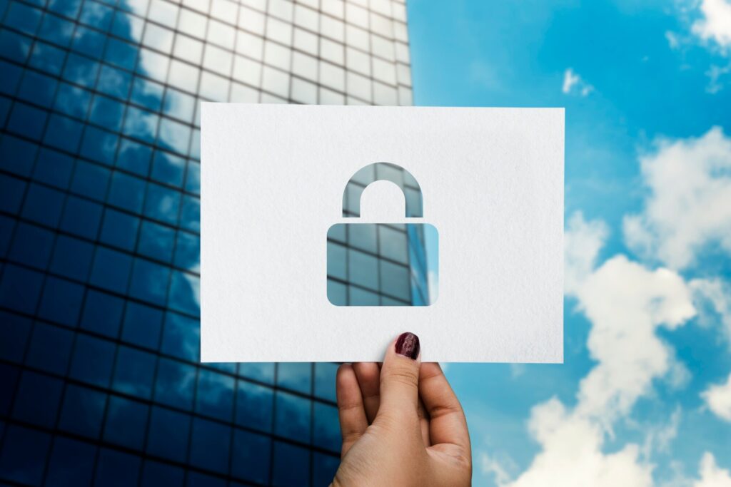 Mão segurando papel com ícone de cadeado recortado, simbolizando segurança nas consultas de CPF e CNPJ em ambientes corporativos.